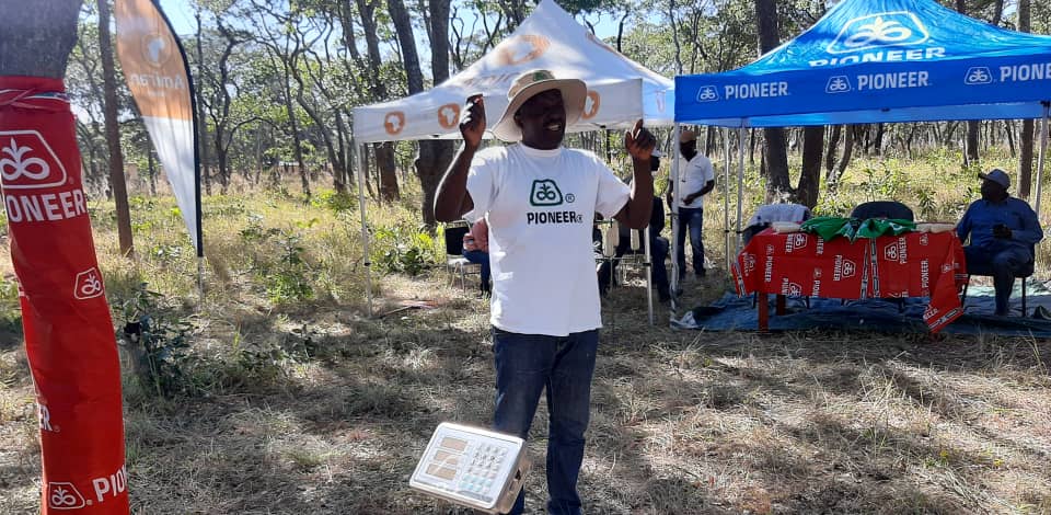 Zambia farmer, Million stands outside of booth tents at Corteva field day, where he learned climate resilient skills to improve the productivity of his agro-business.